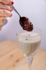 A female hand sprinkles a smoothie with banana, ice cream, and chocolate smoothies.