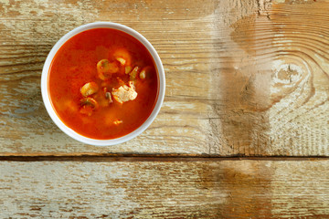 Traditional tom yam soup with chicken in a plate on a wooden table. Horizontal photo