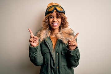 Young african american skier woman with curly hair wearing snow sportswear and ski goggles smiling confident pointing with fingers to different directions. Copy space for advertisement