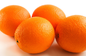 four whole oranges in the skin close up on a white isolated background