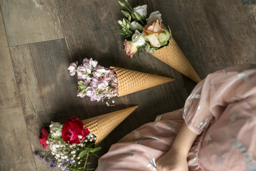 Bouquet of flowers on the floor. Beautiful flowers on a wooden table in ice cream. Romantic bouquet at valentines day. Little girl with ice-cream.
