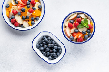 Fresh organic fruit salad with Chia seeds. Healthy breakfast set on grey background. The concept of delicious and healthy food. Top view, copy space