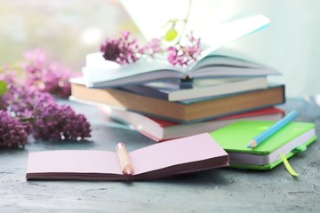 Books, open notebook for notes, lilac flowers on the table, the concept of home schooling, comfortable at home, for education