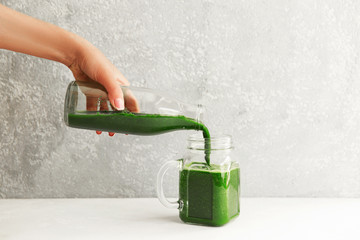 Hands pouring healthy green smoothie in a jar. Clean eating concept