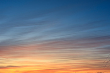 the sky with stripes during dawn is blue and orange.