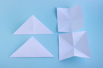 Step 1. Handmade white trendy geometric polygonal paper origami fish on blue background.