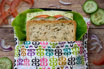 Eco-friendly durable reusable sandwich bag with healthy vegetables on a wooden cutting board. Top view
