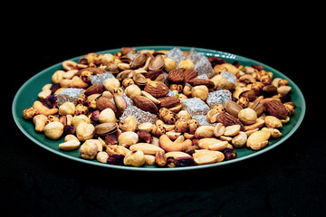 mixed nuts from above. Nuts of granite on a black background. Nuts shot from the top. nuts on a black background. peanut, cashew, roasted chickpea, hazelnut, pistachio, almond, roasted chickpea.