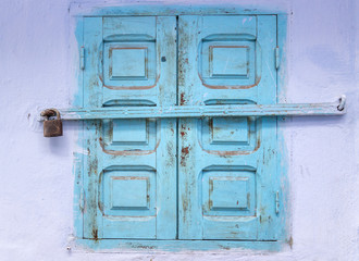 Window with blue wooden shutters closed on padlock. House details in North Africa. Medina of Chefchaouen town, Morocco.