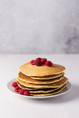Appetizing homemade pancakes with raspberries on a white wooden table
