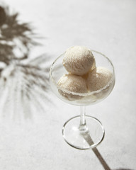 Balls of ice cream in a glass on a sunny day against a bright background