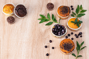 Chocolate muffin and nut muffin, homemade bakery on dark background. Muffin with blueberries on a wooden table. Fresh berries and sweet pastries on the board.