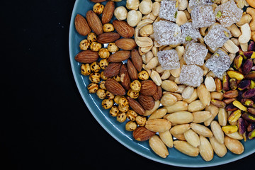 mixed nuts from above. Nuts of granite on a black background. Nuts shot from the top. nuts on a black background. peanut, cashew, roasted chickpea, hazelnut, pistachio, almond, roasted chickpea.