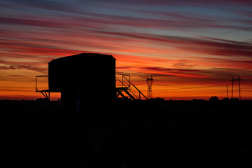 Fototapeta premium the silhouette of a strange iron structure on a field against the background of a beautiful dawn sky