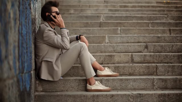 Businessman Sitting On Steps And Talking On Mobile Phone.Freelancer Internet Online Meeting Webinar And Calling.Man Freelance With Smartphone Outdoors.Businessman With Phone On Steps Remote Working.