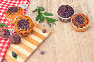 Chocolate muffin and nut muffin, homemade bakery on dark background. Muffin with blueberries on a wooden table. Fresh berries and sweet pastries on the board.