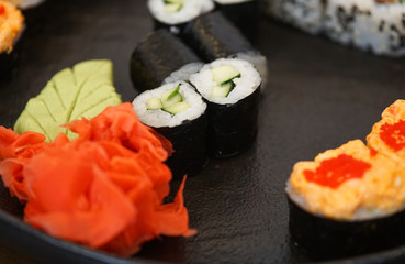 Sushi roll with cucumber, ginger, wasabi. Sushi menu. Japanese food on a black plate.