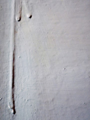 The current white paint on the wall. Brooks of liquid. Vertical flows.