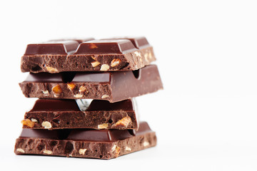 Composition stack of tiles of dark chocolate with nuts close-up on a white background isolated