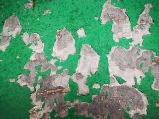 Old green cracked paint on the wall of the building.