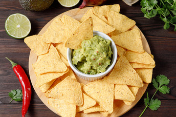 Mexican avocado sauce guacamole with nachos on a wooden background