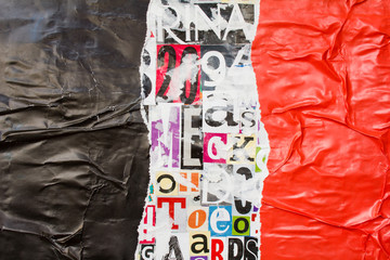Torn and crumpled black and red glossy paper poster on bright colorful collage of magazine paper...