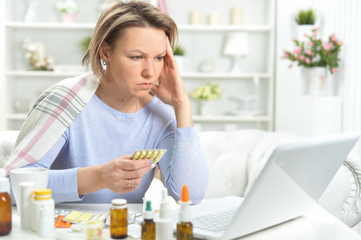 Beautiful young woman with pills using laptop