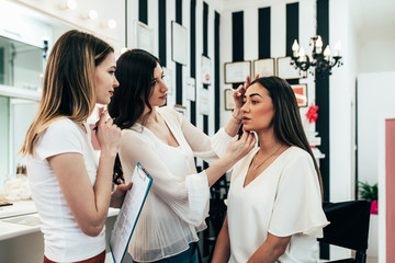 Professional makeup artist teaching student in makeup school.