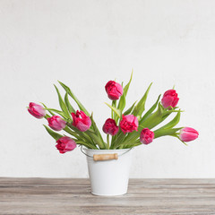 red tulips in bucket on background  old  white wall