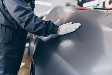 Car wrapping specialist putting vinyl foil or film on car. Selective focus. 