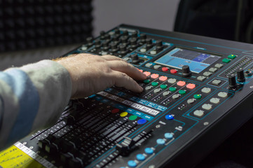 Human hand on the mixing console in the recording Studio.