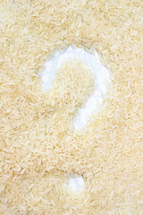 Background of rice grains, with a question mark in the center. The texture of the product.