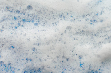 The texture of soap foam flows down from above on a lilac background. The concept of hygiene.