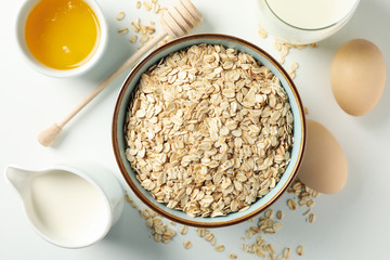 Composition with oatmeal flakes on white background, top view. Cooking breakfast