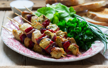 Chicken kebabs with vegetables served with various herbs and sauce.