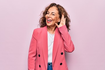 Middle age beautiful businesswoman wearing jacket standing over isolated pink background smiling...