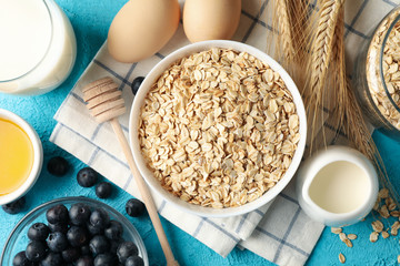 Composition with oatmeal flakes on blue background. Cooking breakfast