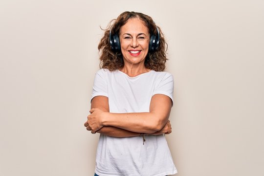 Middle Age Beautiful Woman Listening To Music Using Headphones Over White Background Happy Face Smiling With Crossed Arms Looking At The Camera. Positive Person.