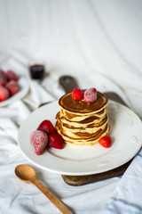 Close-up delicious pancakes, with strawberries and syrup on a light background. Sweet syrup flows from a stack of pancake