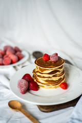 Close-up delicious pancakes, with strawberries and syrup on a light background. Sweet syrup flows from a stack of pancake