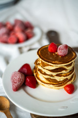 Close-up delicious pancakes, with strawberries and syrup on a light background. Sweet syrup flows from a stack of pancake