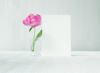 Greeting card with peony flowers on white provence interior. Empty invitation card at modern room.