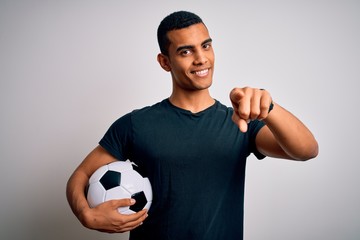 Handsome african american man playing footbal holding soccer ball over white background pointing to...