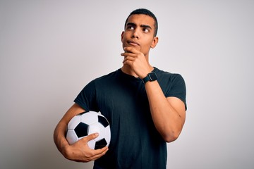 Handsome african american man playing footbal holding soccer ball over white background with hand...