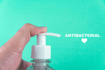 Man hand in container with alcohol gel on the light blue background