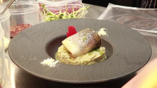 Preparation seabass fish and mashed potatoes. Serve on a black plate.The kitchen of the restaurant. Dish from Chef