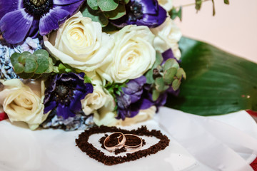 Wedding rings against the background of a bouquet of roses.