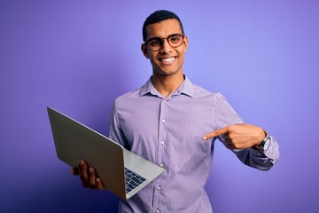 Young handsome african american business man working using laptop over purple background very happy pointing with hand and finger
