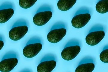 Avocado with shadows on a blue background. Avocado texture top view. Banner. Pop art design, creative summer food concept.