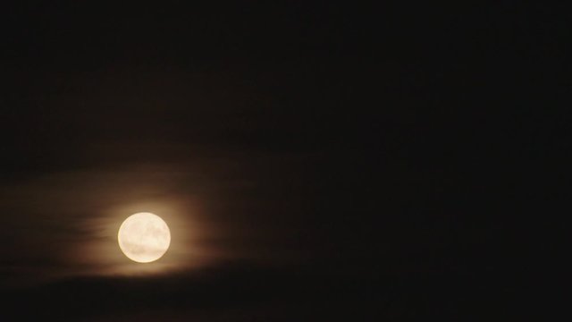 Perfect full moon shining through wispy clouds at night